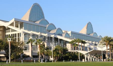 Modern Orlando Convention Center building with distinctive glass archways and green lawn.