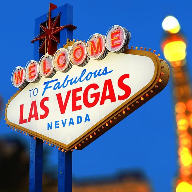Iconic Welcome to Fabulous Las Vegas sign glowing brightly against a blue sky.